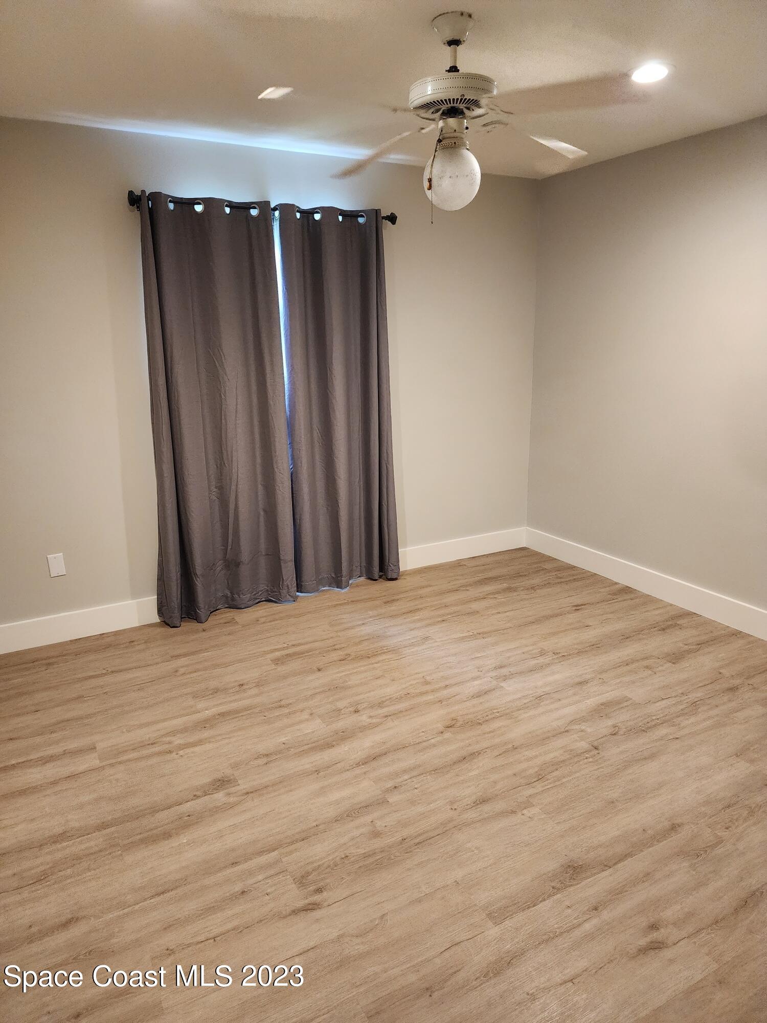 708 Fishtail Palm Boulevard Melbourne, FL 32901 - Photo 16 of 33 an empty room with wooden floor fan and windows