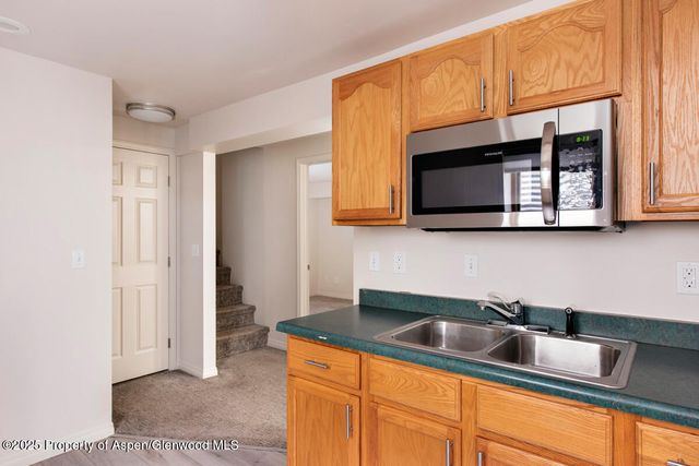 a kitchen with stainless steel appliances granite countertop a sink a microwave cabinets and a wooden floor