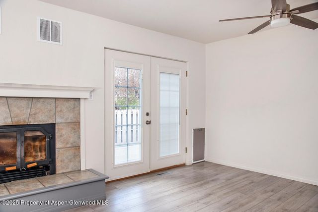 a view of an empty room with wooden floor and a fireplace