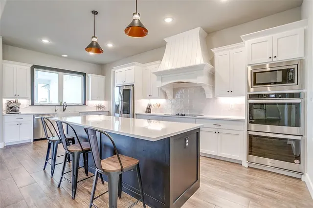 a kitchen with stainless steel appliances granite countertop a stove a sink a microwave a dining table and chairs