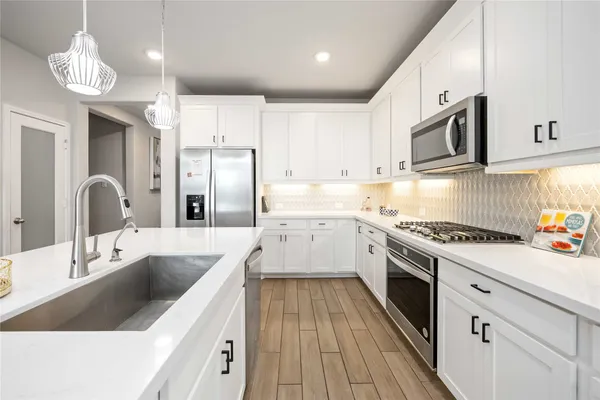 a kitchen with stainless steel appliances granite countertop a sink a stove and a refrigerator