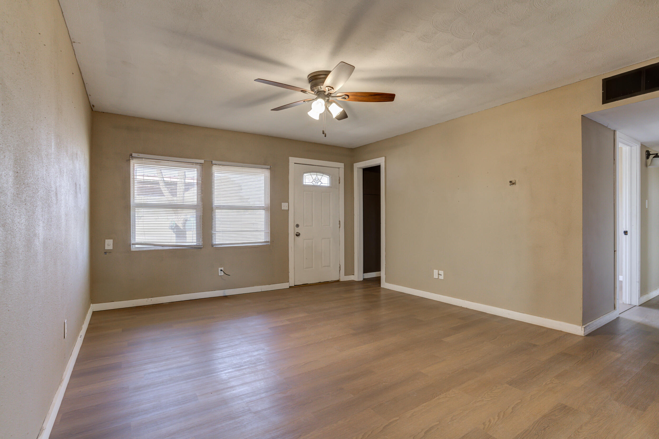 3204 East 2nd Street Lubbock, TX 79403 - Photo 8 of 34 an empty room with wooden floor chandelier fan and windows