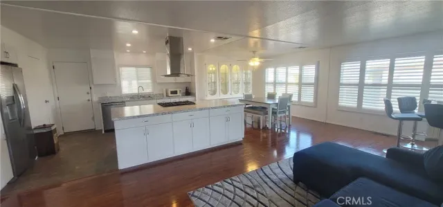 a kitchen with stainless steel appliances granite countertop a stove a sink a refrigerator and white cabinets with wooden floor