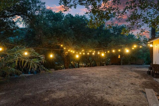 a view of a patio with table and chairs potted plants and large tree