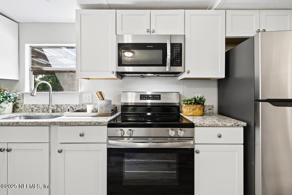 28 Neighbors Cove Road Orange Park, FL 32065 - Photo 21 of 56 a kitchen with stainless steel appliances granite countertop a stove a sink and a microwave