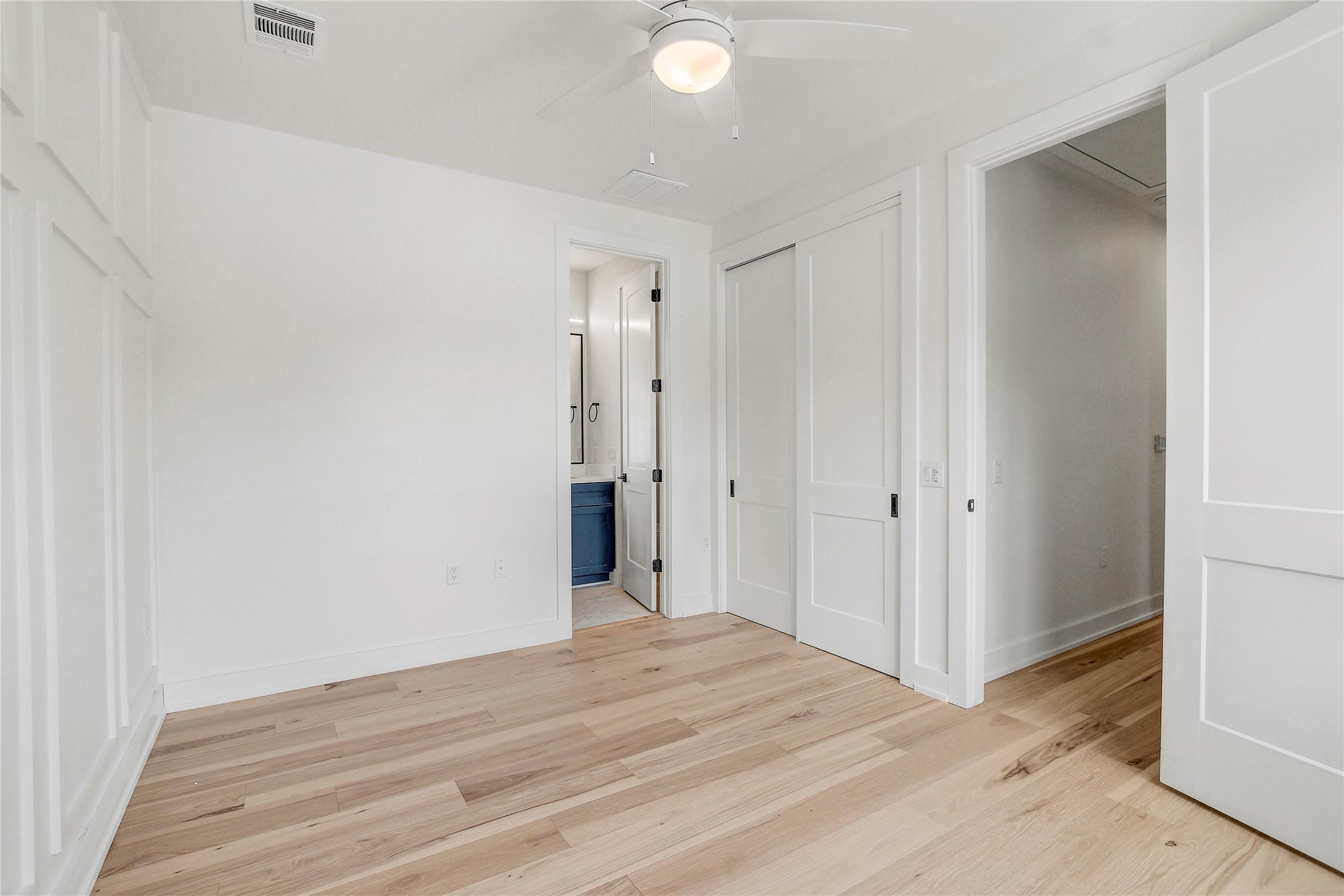 4127 East 12th Street, Unit 2 Austin, TX 78721 - Photo 25 of 28 Unfurnished bedroom featuring light wood finished floors, baseboards, ensuite bathroom, and a ceiling fan