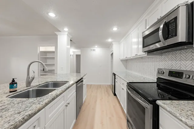 a kitchen with stainless steel appliances granite countertop a sink stove and microwave
