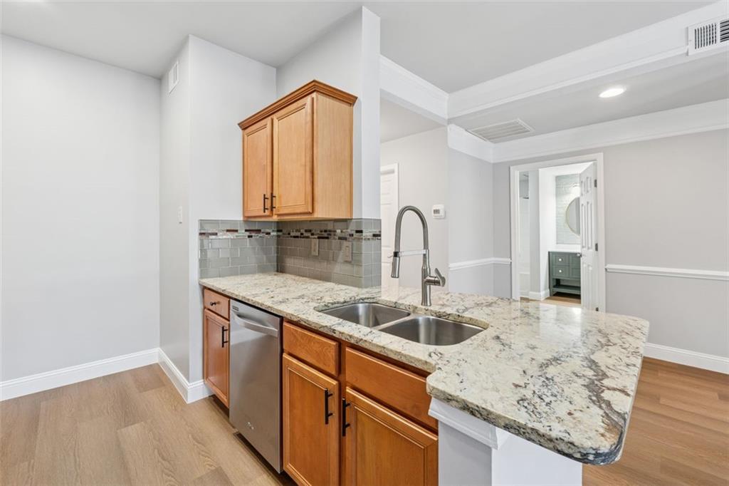 2700 Pine Tree Road Northeast, Unit 1115 Atlanta, GA 30324 - Photo 11 of 29 a kitchen with stainless steel appliances granite countertop a sink a stove and a wooden floors