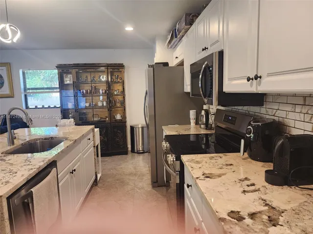 a living room with stainless steel appliances kitchen island granite countertop a table chairs and a view of living room