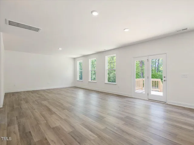 a kitchen with stainless steel appliances granite countertop a stove a sink and white cabinets with wooden floor next to windows