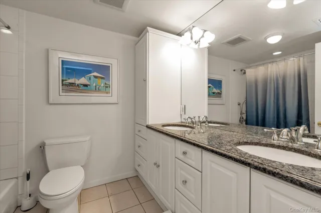 a bathroom with a granite countertop sink toilet and large mirror