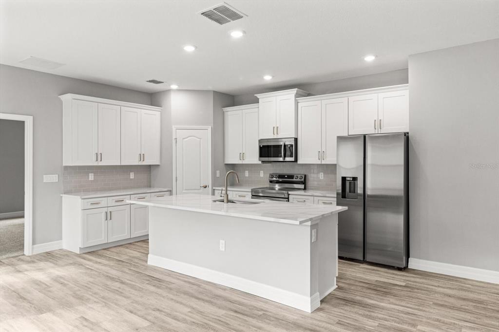 9 Fringetree Street Homosassa, FL 34446 - Photo 11 of 37 a kitchen with stainless steel appliances a sink stove refrigerator and white cabinets with wooden floor