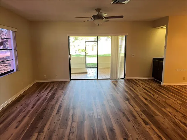 a view of empty room with wooden floor and fan