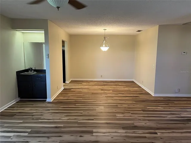 a view of a livingroom with an empty space hardwood floor and a ceiling fan