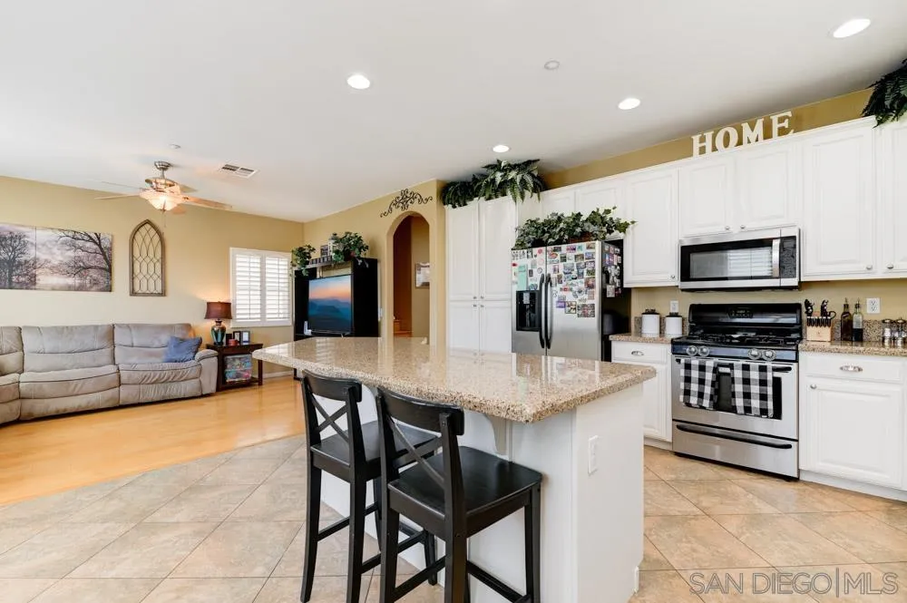 8713 Glen Oaks Way Santee, CA 92071 - Photo 3 of 22 a kitchen with stainless steel appliances kitchen island granite countertop a table chairs sink and cabinets