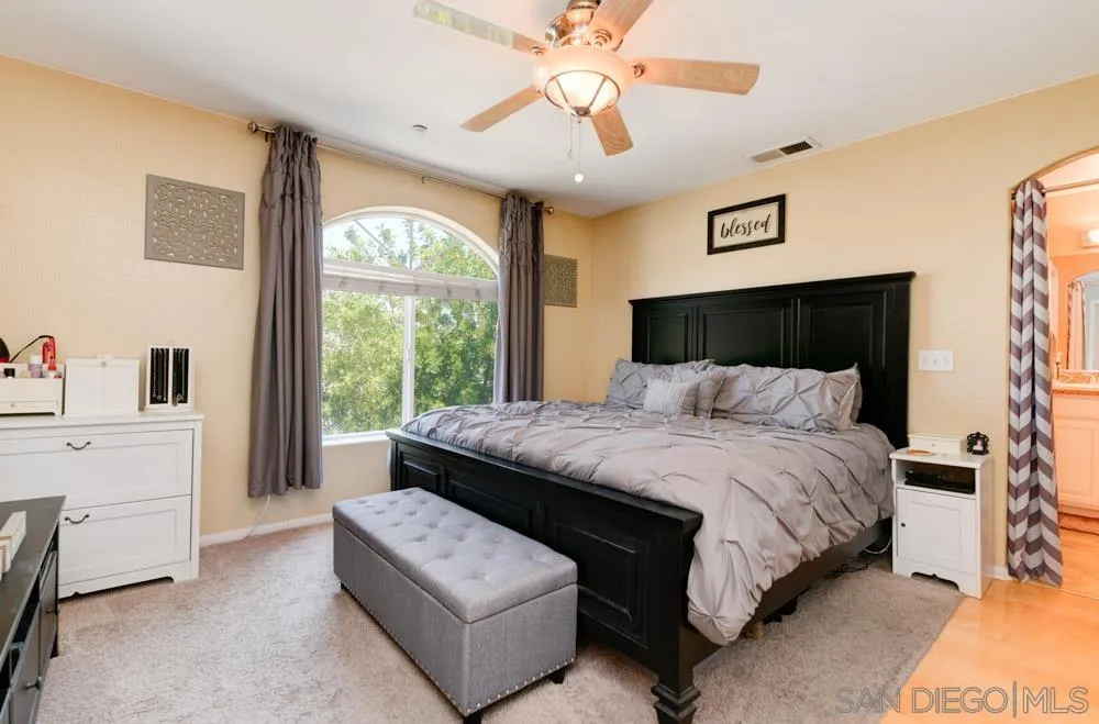 8713 Glen Oaks Way Santee, CA 92071 - Photo 9 of 22 a bedroom with a large bed and a chandelier fan