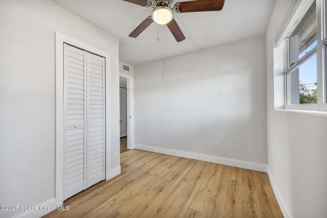 an empty room with wooden floor cabinet and windows