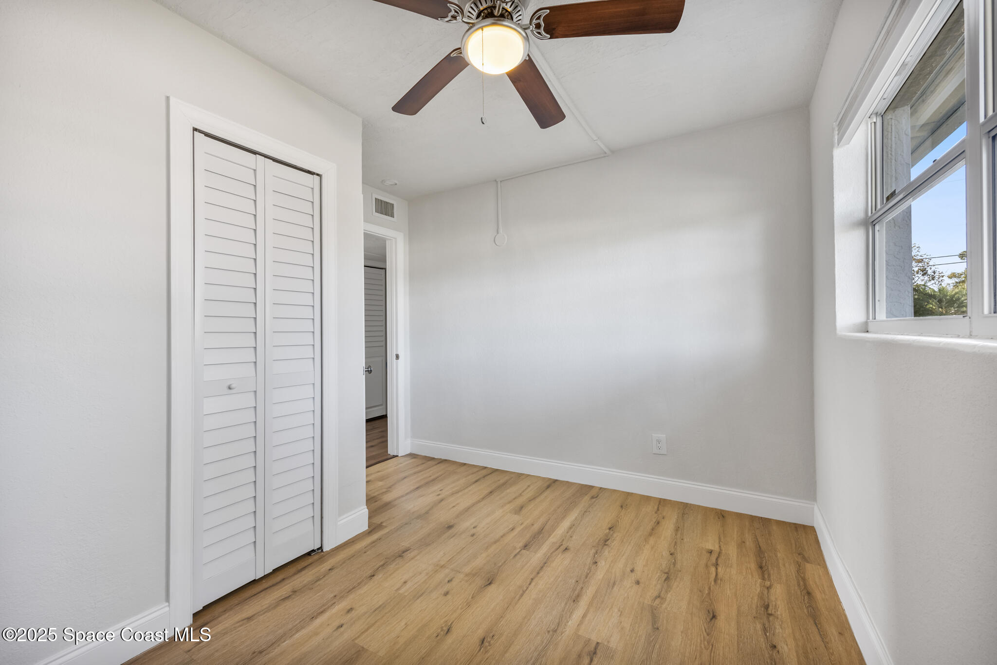 1107 Alamanda Lane Cocoa, FL 32922 - Photo 12 of 24 an empty room with wooden floor cabinet and windows