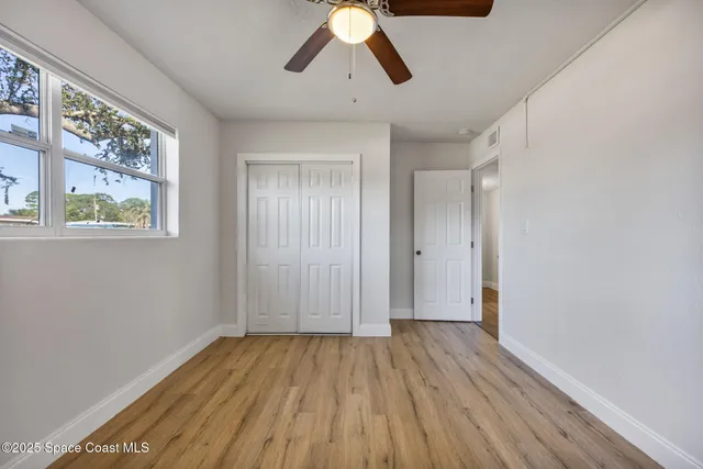 a view of empty room with wooden floor and window