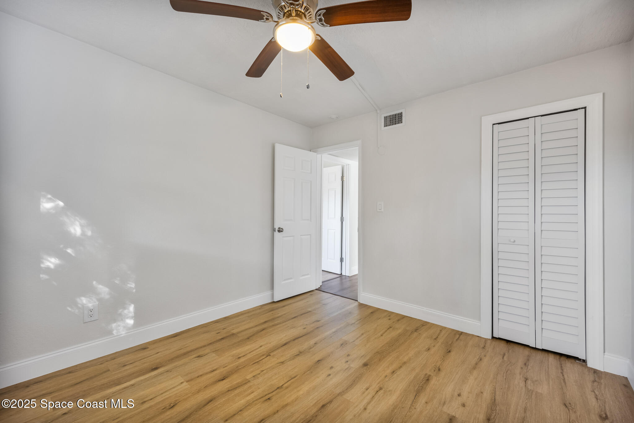 1107 Alamanda Lane Cocoa, FL 32922 - Photo 16 of 24 a view of an empty room with wooden floor and a ceiling fan