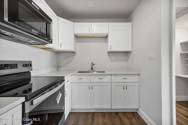 a kitchen with granite countertop a sink cabinets and stainless steel appliances
