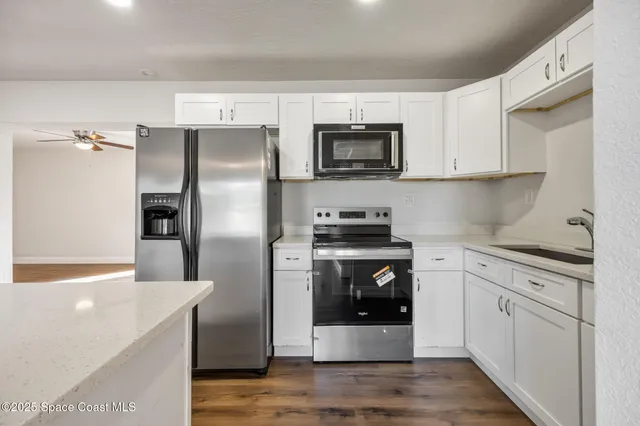 a kitchen with cabinets stainless steel appliances and wooden floor