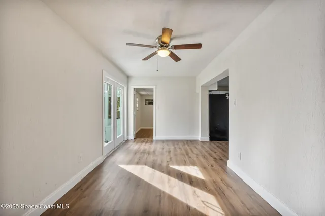 a view of empty room with wooden floor and fan