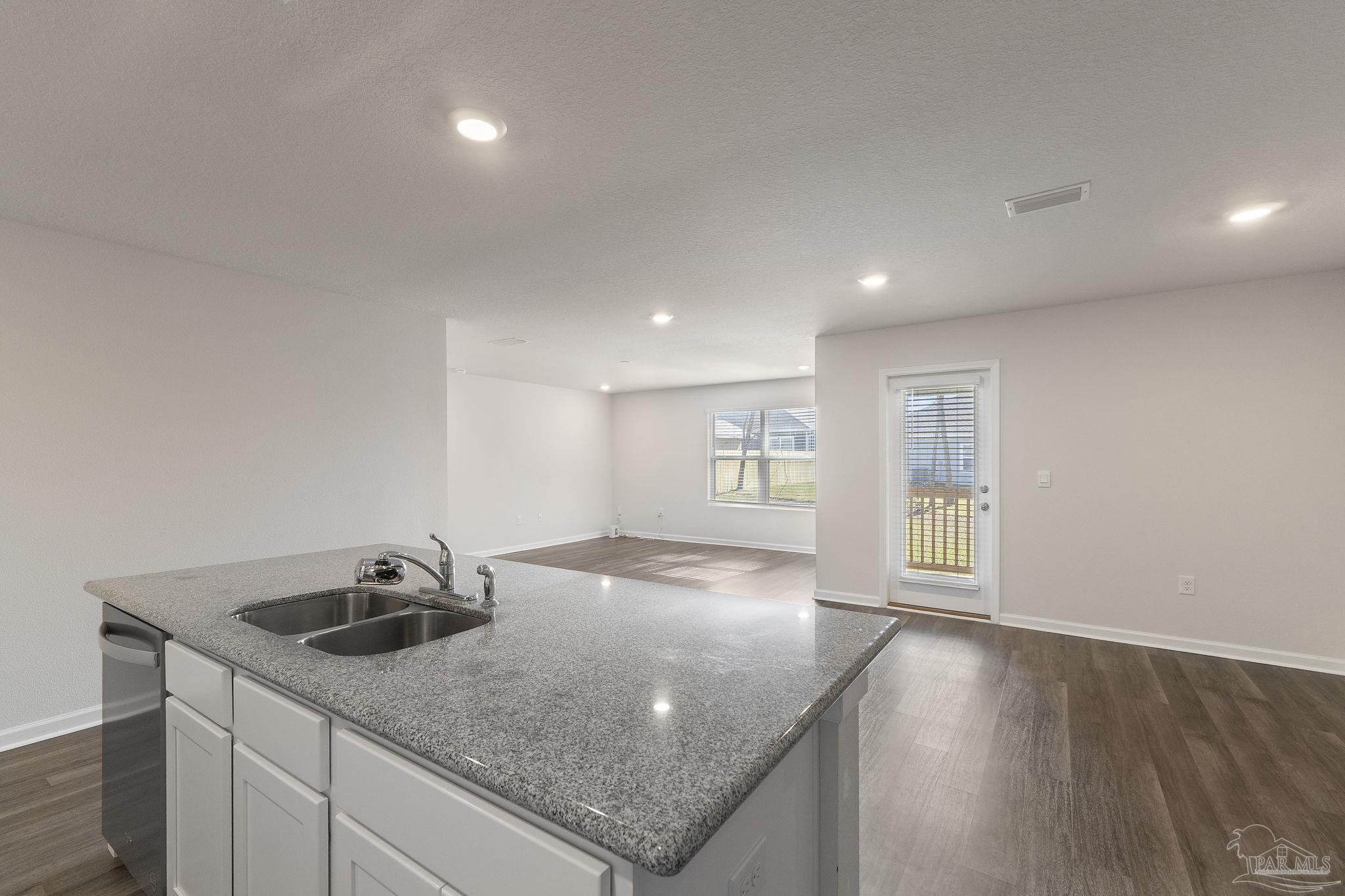 8669 Pathstone Boulevard Pensacola, FL 32526 - Photo 16 of 36 a view of a kitchen island a sink a window and wooden floor