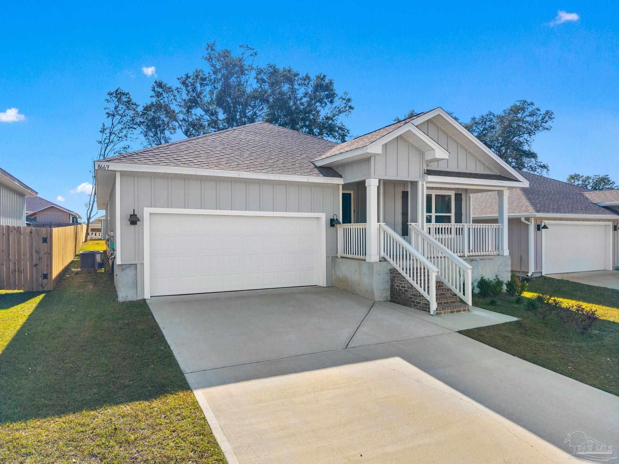 8669 Pathstone Boulevard Pensacola, FL 32526 - Photo 3 of 36 a view of a white house with a yard and table and chairs under an umbrella