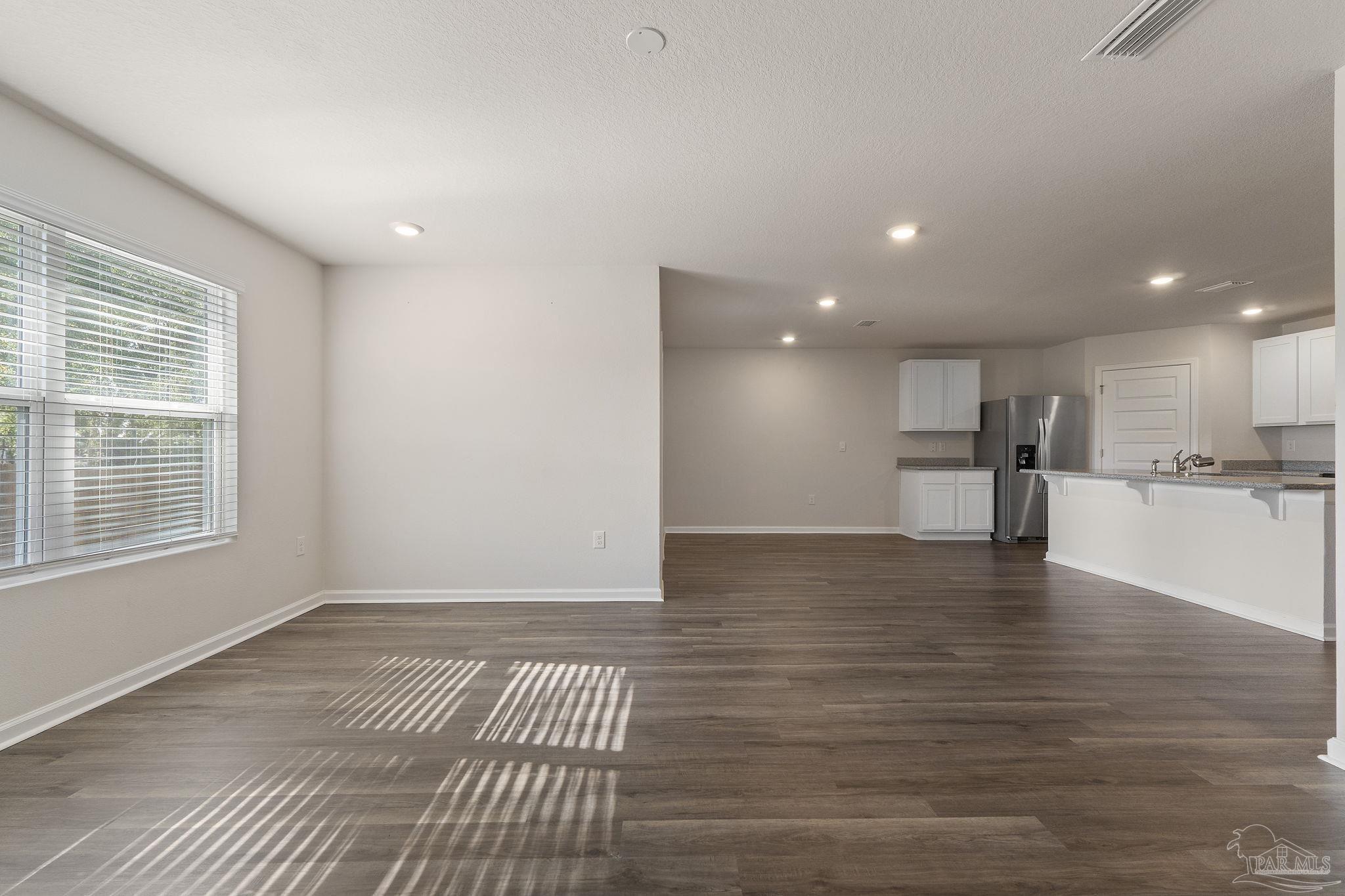8669 Pathstone Boulevard Pensacola, FL 32526 - Photo 7 of 36 a view of empty room with wooden floor and kitchen