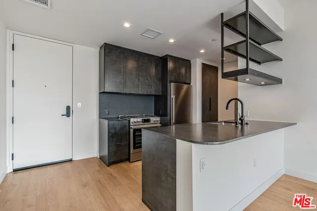 a kitchen with stainless steel appliances granite countertop a sink a stove and a refrigerator