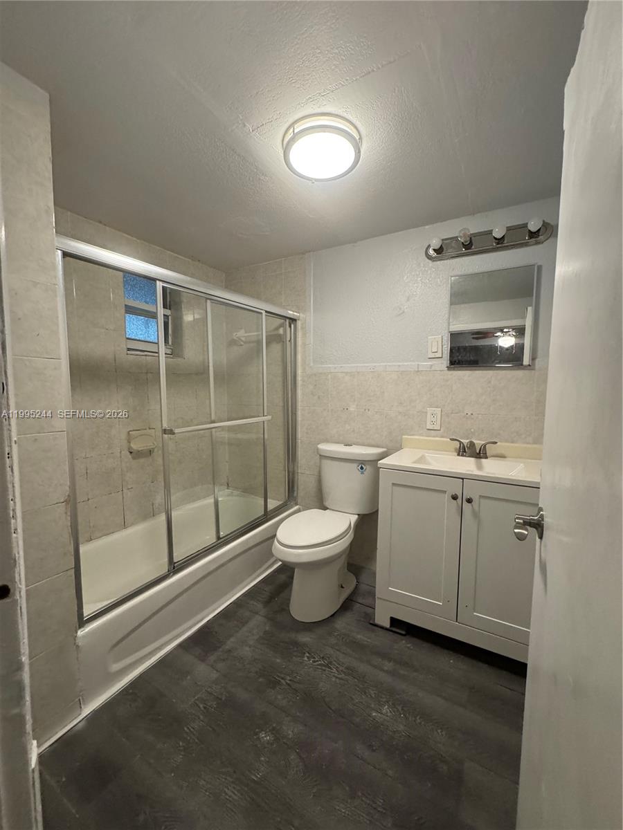7802 Northwest 8th Avenue, Unit 5 Miami, FL 33150 - Photo 6 of 7 a bathroom with a granite countertop toilet a sink a mirror and shower