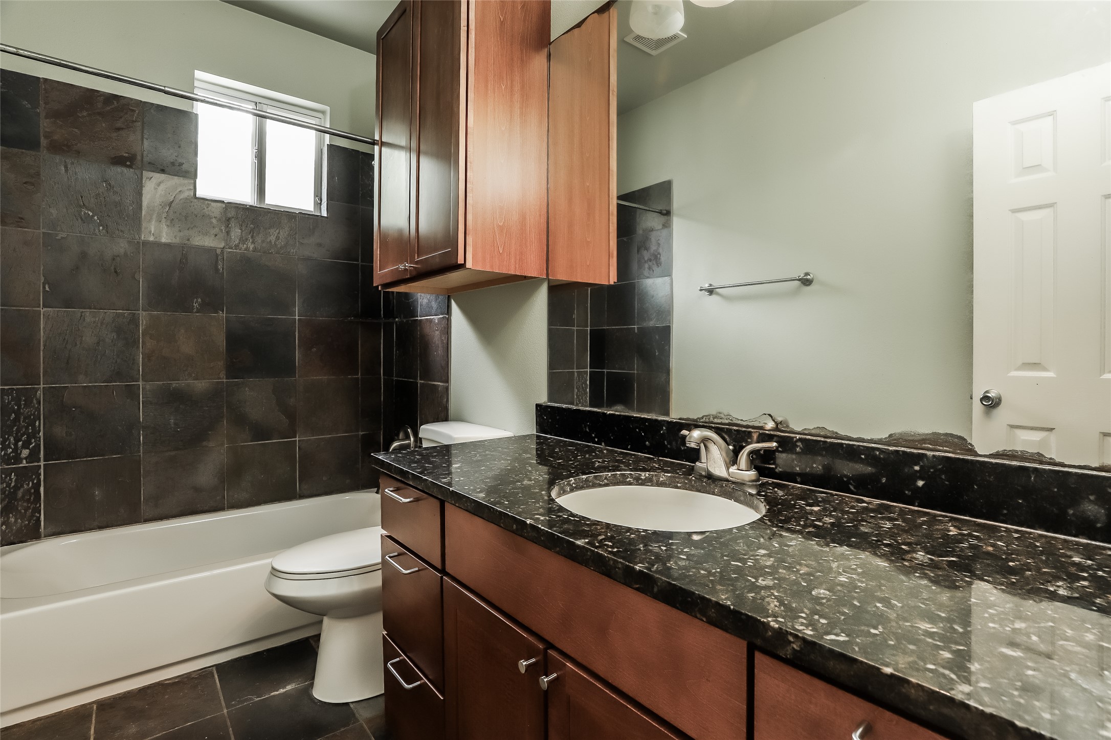1701 Sanchez Street, Unit A Austin, TX 78702 - Photo 16 of 19 A well-appointed bath features a deep soaking tub and a sleek dark granite vanity, perfect for unwinding.