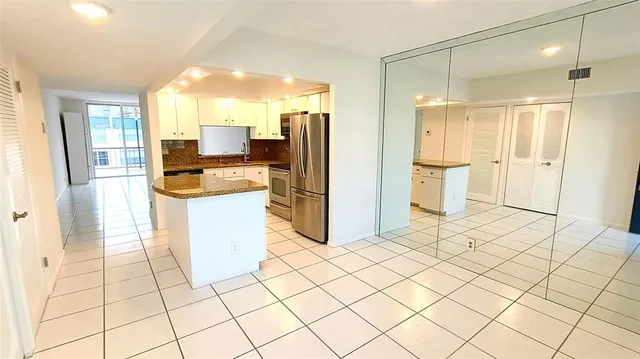 a kitchen with a refrigerator a stove a sink and a dining table chair