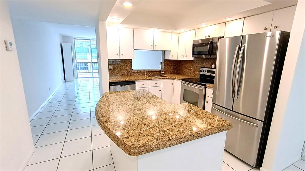 777 South Federal Highway, Unit M301 Pompano Beach, FL 33062 - Photo 2 of 16 a kitchen with granite countertop a refrigerator and a stove top oven