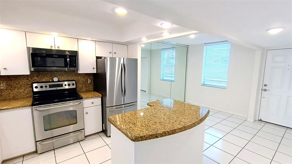 777 South Federal Highway, Unit M301 Pompano Beach, FL 33062 - Photo 3 of 16 a kitchen with kitchen island granite countertop a sink a stove a microwave a counter top space and cabinets