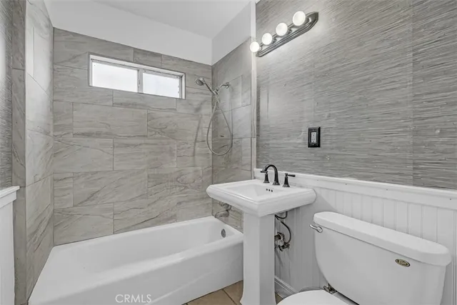 a bathroom with a sink a toilet a mirror and shower