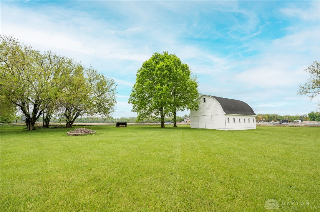 190 Swailes Road Troy, OH 45373 - Photo 79 of 82 Expansive green yard with a classic white barn under a bright sky.