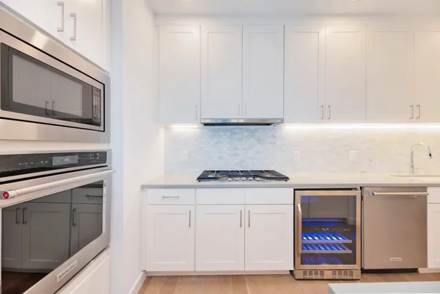 a kitchen with granite countertop white cabinets and stainless steel appliances