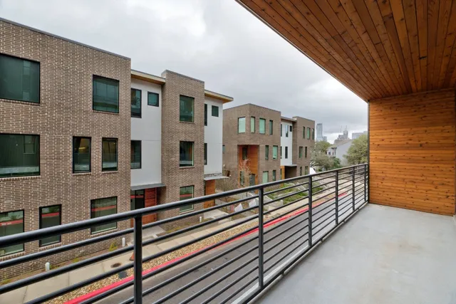 a view of balcony with two buildings and wooden fence