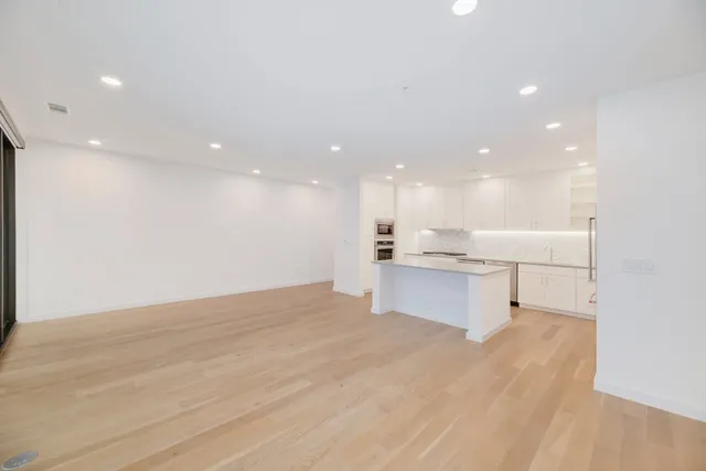 a view of kitchen with kitchen island a sink wooden floor and view living room