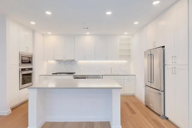 a kitchen with stainless steel appliances a refrigerator and a stove top oven