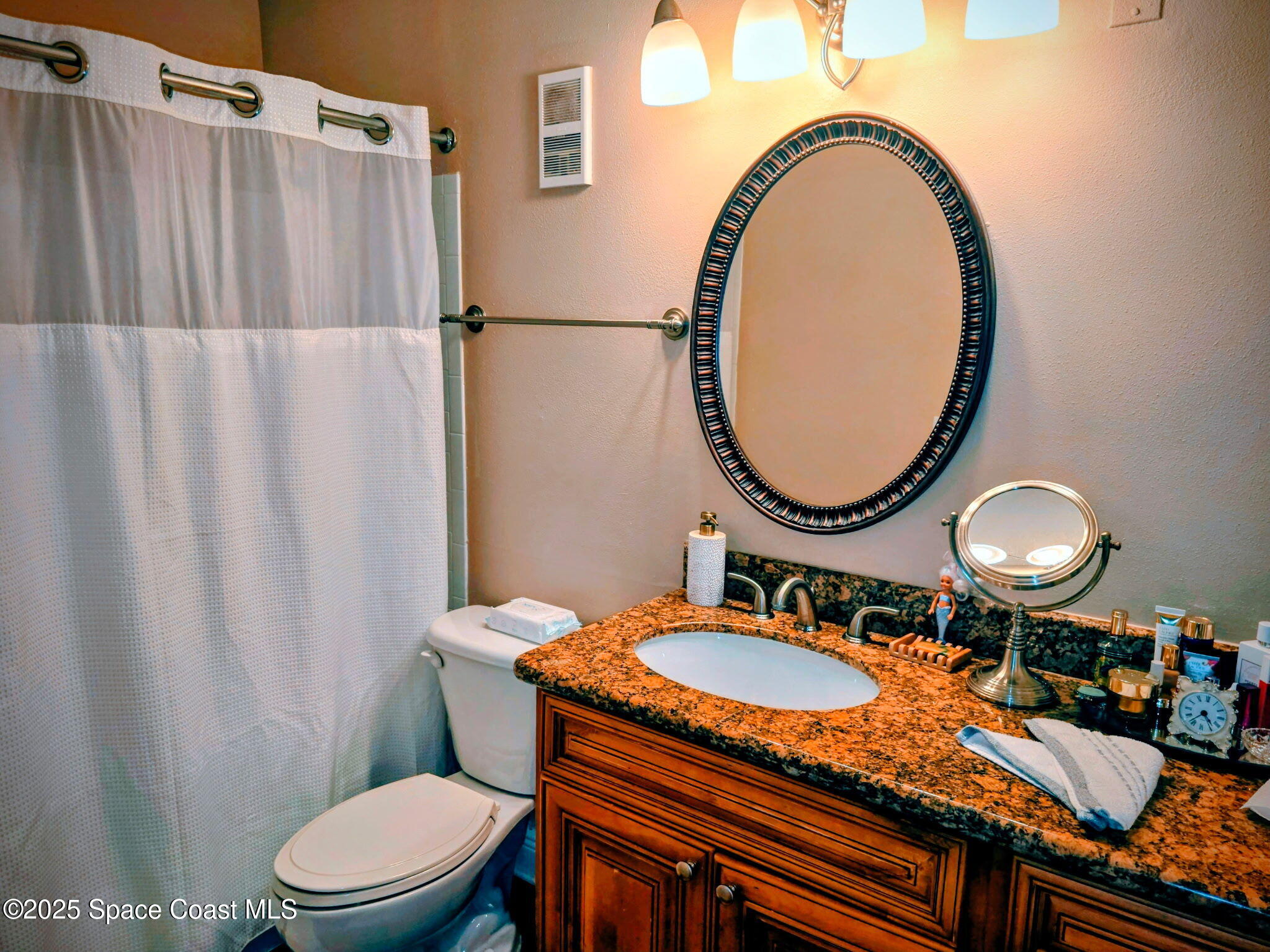 7667 North Wickham Road, Unit 416 Melbourne, FL 32940 - Photo 12 of 30 a bathroom with a granite countertop sink mirror vanity and a toilet
