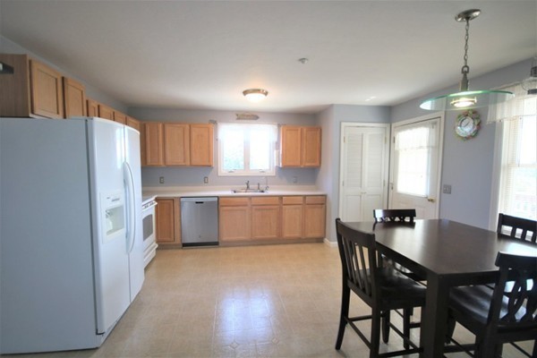 25 George Street, Unit 5 Dudley, MA 01571 - Photo 7 of 42 a kitchen with a table chairs a sink dishwasher a refrigerator and cabinets