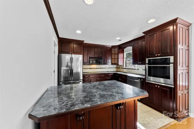 a kitchen with kitchen island a counter space a sink appliances and cabinets