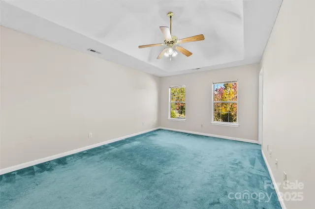an empty room with windows and ceiling fan