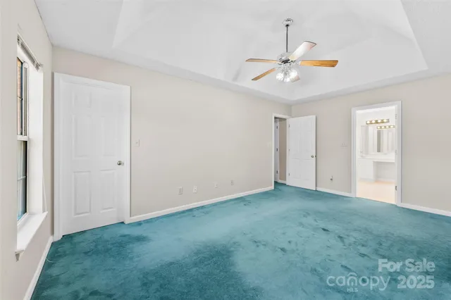 a view of an empty room and chandelier fan