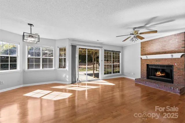 a view of an empty room with windows and a fireplace