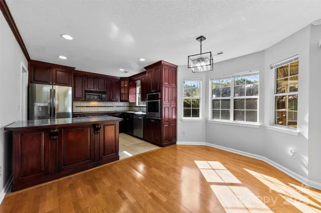a kitchen with stainless steel appliances granite countertop a refrigerator and wooden cabinets