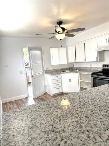 a kitchen with granite countertop a stove a sink and a refrigerator